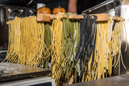 Close up, macro. Street food, night festival. Freshly prepared tagliatelle (pasta) is dried in a wooden dryer.の写真素材
