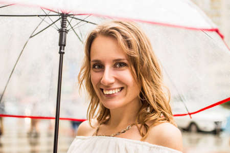 Close up. A woman is holding a transparent umbrella and smiling happily.の写真素材