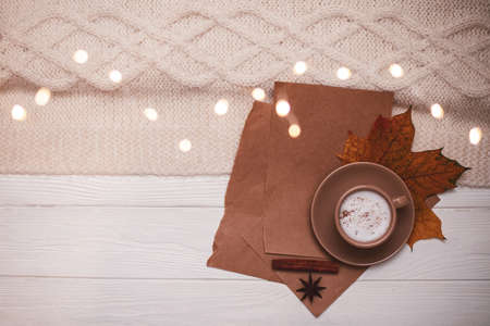 Close up. Top view, flat lay. Seasonal background in white and brown colors. A cup of cappuccino on a white background near a knitted plaid. Copy space.の写真素材