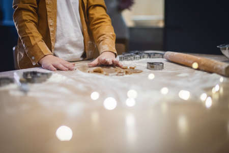 Close up. Children's hands make gingerbread from the dough. There is a Christmas garland on the table. Copy space.の写真素材