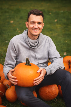 Portrait of smiling man holding big pumpkin at pumpkin farm.の写真素材