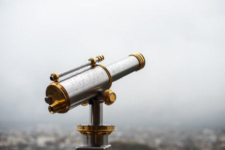 Close up, crop. An observation telescope on the Eiffel Tower in Paris. Foggy rainy city on the background.の写真素材