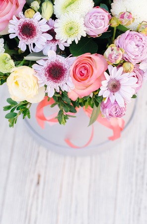The composition of flowers in the box is photographed from above. The flower arrangement consists of roses, chrysanthemum and eustoma. On the back, blurred wooden texture.の写真素材