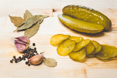 Pickled cucumbers, garlic and spices on a wooden boardの写真素材