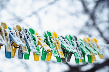 Colored clothespins on the clothesline are covered with frost in winterの写真素材