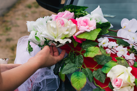 The process of decorating a wedding car with artificial flowers and draperyの写真素材