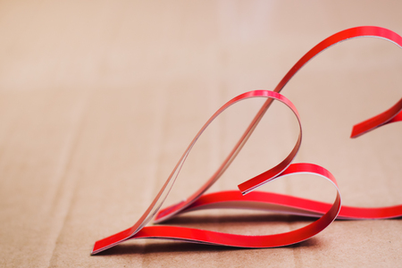 Two homemade paper red hearts on a cardboard background close up, the symbol of Valentine's Day and love.の写真素材