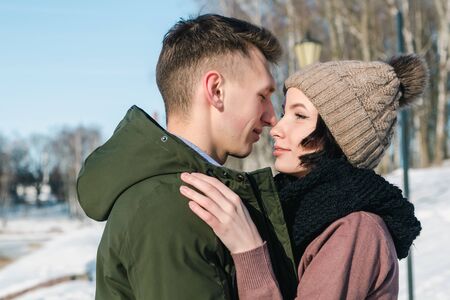 Young couple in love hugging in the park in winter sunny day close up