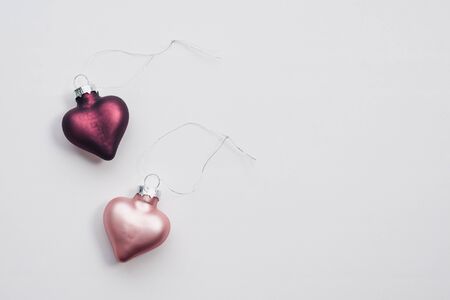 Two Christmas decorations in the form of a pink and plum-colored heart with copy space on a white backgroundの写真素材