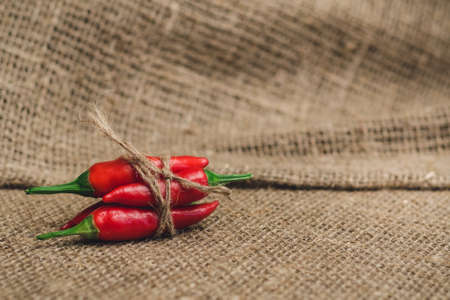 Small red hot peppers tied with jute thread on a linen napkinの写真素材
