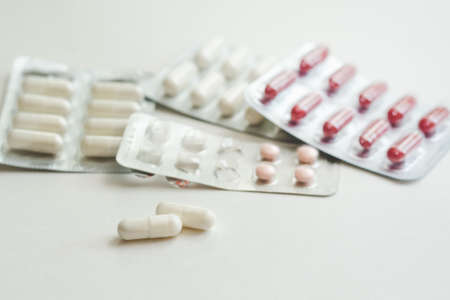 Capsules with medicine and vitamins in blisters and on a white surface, selective focusの写真素材