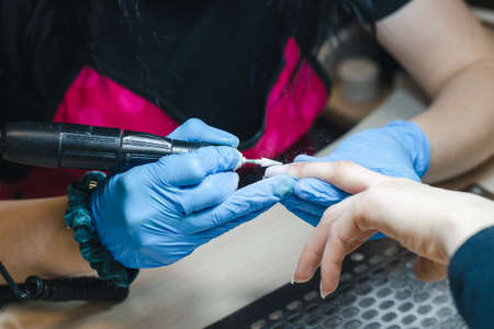 The manicurist removes the old gel from the nails using the hardware methodの写真素材