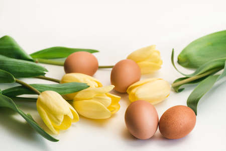 Bouquet of yellow tulips and brown chicken eggs on a white background. Easter card conceptの写真素材