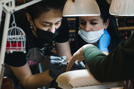 A manicure master teaches a colleague his profession in a cozy atmosphere of a nail service salonの写真素材