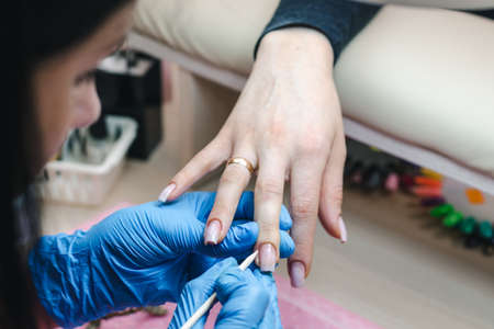 Manicurist pushes the cuticle of the nail with an orange stick, close-upの写真素材
