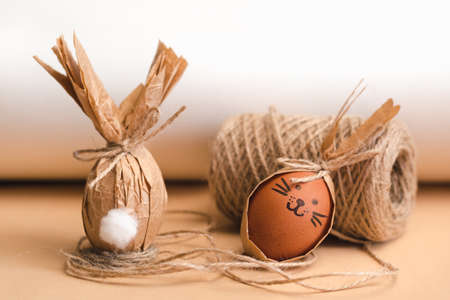 Gift Easter eggs in brown craft paper in the shape of a rabbit and a skein of jute threadsの写真素材