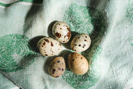 Five spotted quail eggs on a linen tablecloth in natural light, laid out in a flower shapeの写真素材