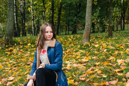 Beautiful girl with long hair in an autumn parkの写真素材