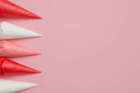 Multicolored glazing in icing bags and star shaped sprinkles on the pink table. Set for decorating desserts. Icing for gingerbread, brownies and cakes in pastry bags. Cake decorating tools.の写真素材