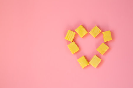 The candy is laid out in the form of a heart. A heart of chewy candies on a pink background. Valentine's Day greeting card. Template for the design. copy space.の写真素材