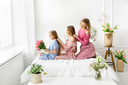 Mom and daughters comb and braid each other's hair.