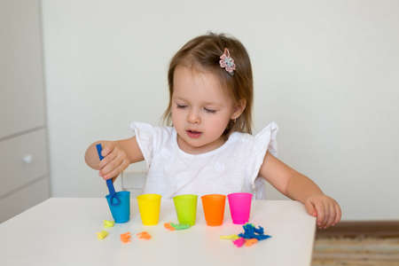 The child learns colors. A little girl sorts the animal figures by color, throwing them into the appropriate cupの写真素材