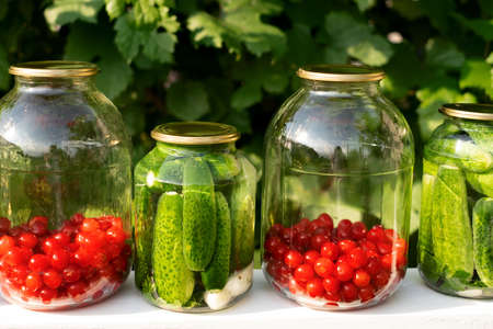 Pickled canned cucumbers and compote of fresh cherries in jars preserves vitamins. canned food. Harvesting of fruits and vegetablesの写真素材