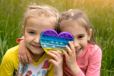 Two little girls play with a modern heart-shaped antistress toy.の写真素材