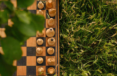 An old chess board with pieces placed on the grass at the start. Copy space. International Chess Day. World Chess Federation, FIDEの写真素材