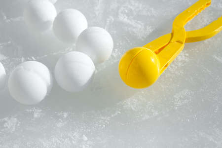 A tool for modeling and making snowballs from snow for children's winter games. Snowballs lying on the frozen ice next to a plastic instrument shine in the rays of the sun. Snowball Tongs.frozen waterの写真素材