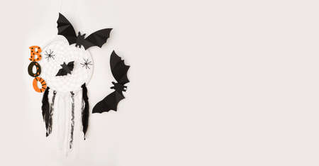 Bats and a dream catcher with cobwebs and spiders on a white background is a Halloween concept. A copy of the space. Banner. The orange-black word "boo"の写真素材