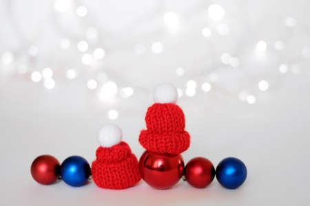 Blue and red Christmas balls, which are wearing a warm knitted cap with a pompom. Unfocused background with silver bokeh. The concept of Christmas and New Year. Winter holidays. copy spaceの写真素材