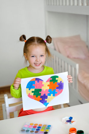 Kid drew a picture of a heart from puzzles as a gift to a friend suffering from autism. Teaching tolerance, tolerance and awareness. Learning tolerance, tolerance and awareness for people with diseaseの写真素材
