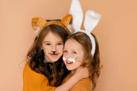 Kids with painted faces in guise of rabbit and tiger. Zodiac 2023 year according to Chinese calendar. Girl dressed up with bunny ears and makeup in anticipation new year. Symbol outgoing old year 2022の写真素材