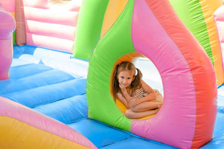 Baby girl in an colorful inflatable castle attraction for entertaining funny jumping