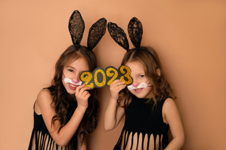 Girls with black bunny ears hold the golden number 2023 in their hand. The water rabbit is a symbol of the new yearの写真素材
