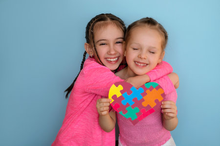 A cute beautiful girl hugs her sister with autism syndrome holding a heart-shaped card. Caring, love and support of loved ones. autism spectrum diseaseの写真素材