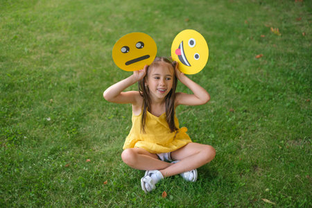 Funny humorous laughing girl waving paper emoticons with a variety of faces and emotionsの写真素材