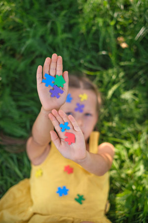 Close-up of the girl's palms, strewn with colored paper puzzles, Symbolizing autismの写真素材