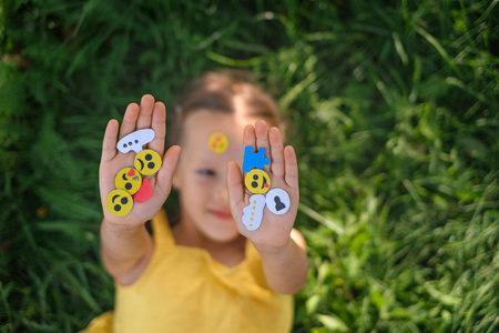The child shows paper web icons and emojis used to communicate on social networks and to describe a...