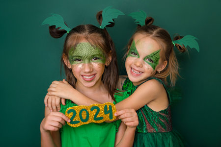 Girls dressed up as a green dragon, the symbol of the new year according to the Chinese calendar, hold the numbers 2024.の写真素材