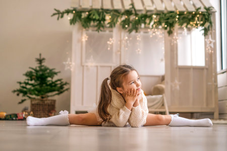 A thoughtful gymnast girl is sitting in a twine pose in a room decorated for the new year and looks awayの写真素材