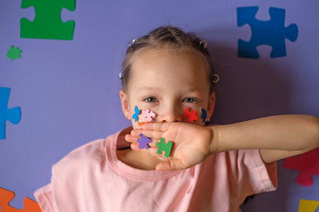 A child with details of multicolored puzzles in hand closes mouth, symbolizing silence. Problems of social perception of people with autism.の写真素材