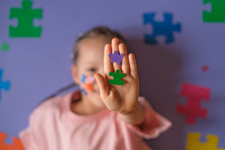Colored puzzles in a child's hand close-up on a purple background. A concept on education and...