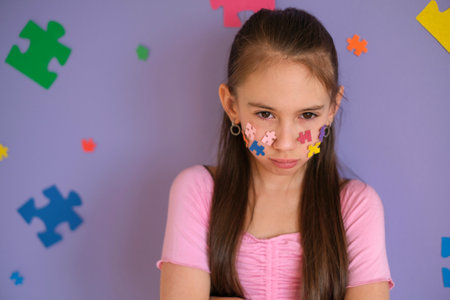 A sad, tearful little girl on a background decorated with puzzles. Bullying of children. The...