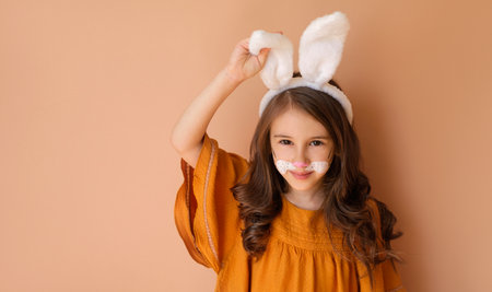 A cute girl in the guise of an Easter bunny adjusts the ear of her headdress. Easter Day Bannerの写真素材