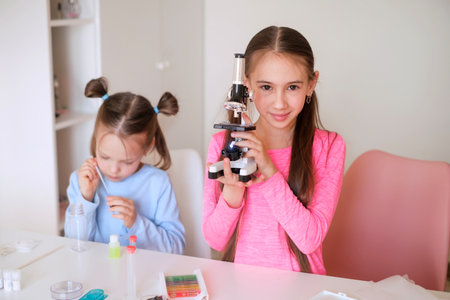 A girl demonstrates a microscope for children's experiments at home. Pre-school educationの写真素材