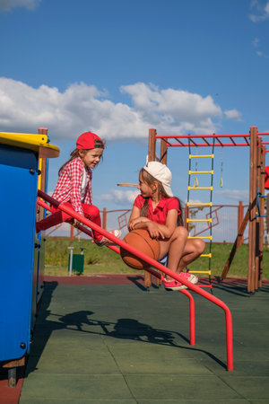 Children on the playground relax while sitting with a ball after playing basketballの写真素材