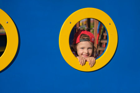 Funny girl peeks through a hole in the playgroundの写真素材