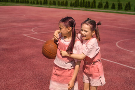Children on the sports court relax after playing basketball. A red-coated sports field.の写真素材